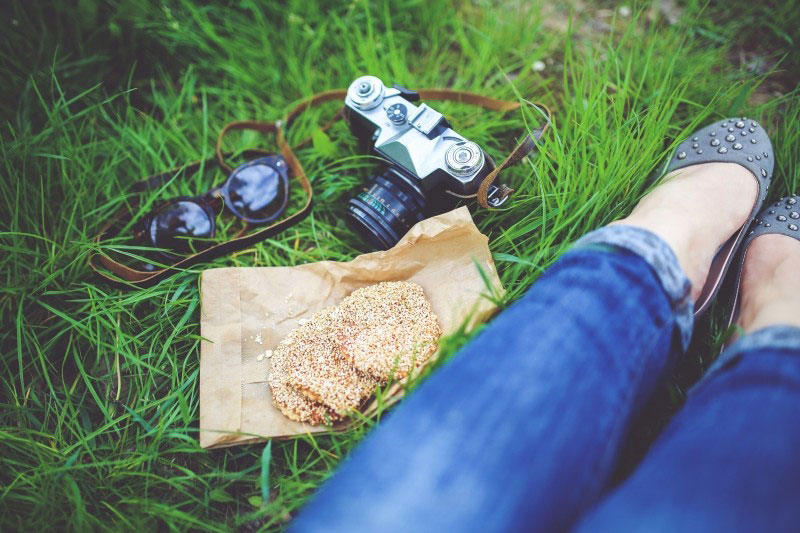 A woman resting in grass with camera and cookies
