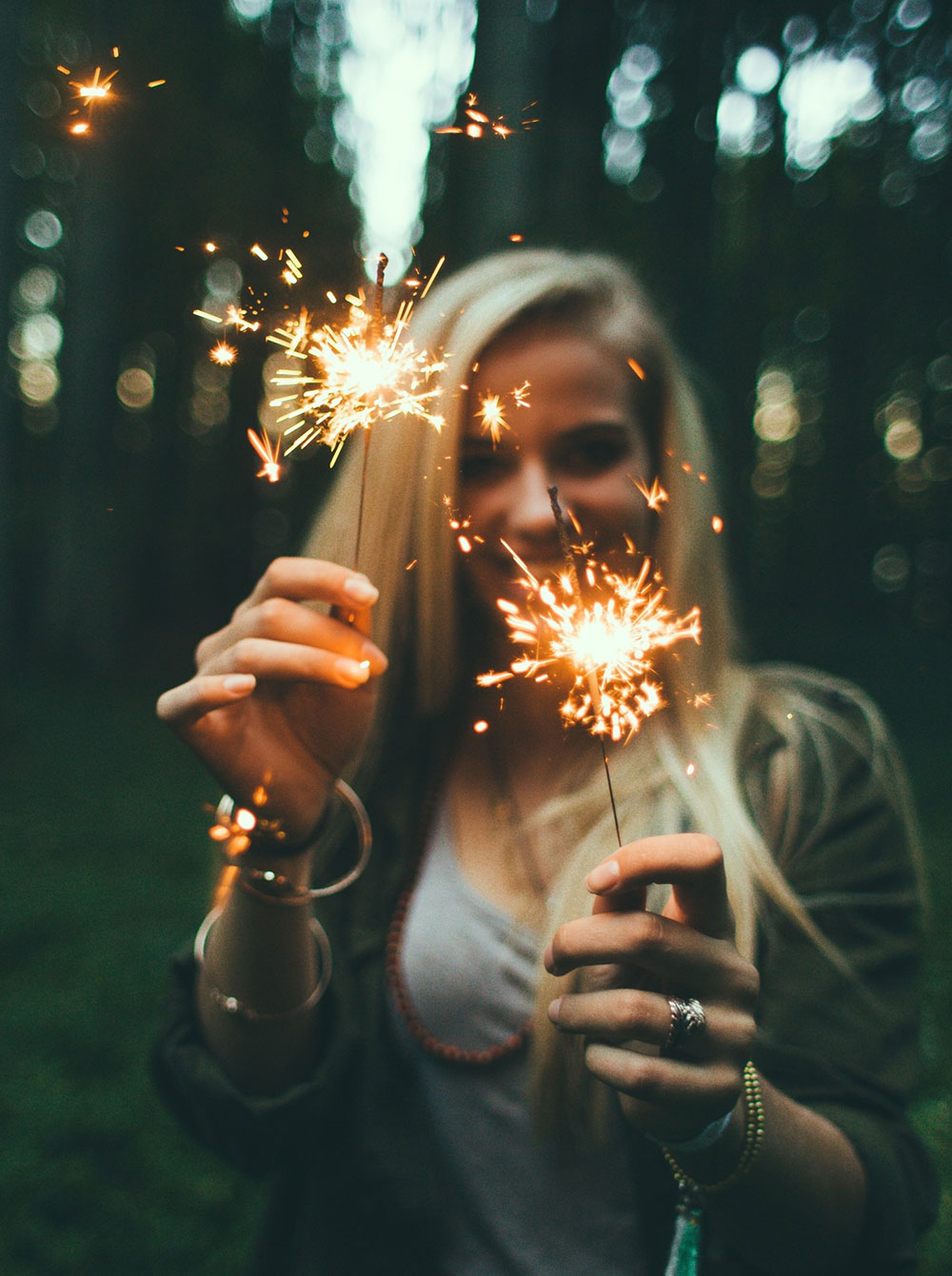 Photo of a woman in the woods with sparklers